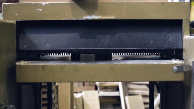 Close up of a wooden board passing through a thickness planer machine