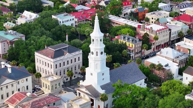 Aerial view of St. Michael's Anglican Church steeple and surrounding Charleston, South Carolina neighborhood cityscape with historical buildings in lowcountry landscape - 4K Drone