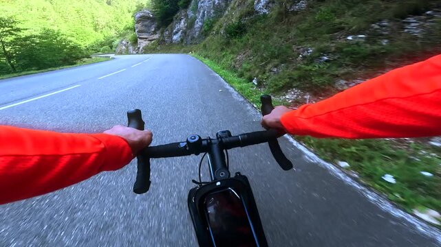 POV road cycling through rocky mountain gorge on winding alpine road
