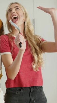 Vertical video: Grabbing spatula, woman in red ringer tee miming song, celebrating cake in kitchen