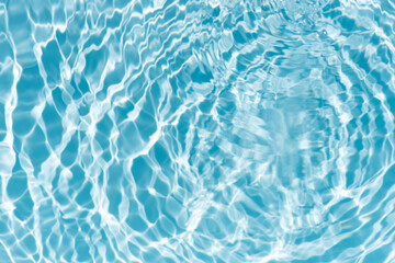 Obraz premium Blue water with ripples on the surface. Defocus blurred transparent blue colored clear calm water surface texture with splashes and bubbles. Water waves with shining pattern texture background.