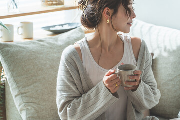 リビングでモーニングコーヒーを飲むおしゃれなアジア人女性