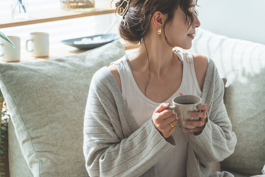 リビングでモーニングコーヒーを飲むおしゃれなアジア人女性