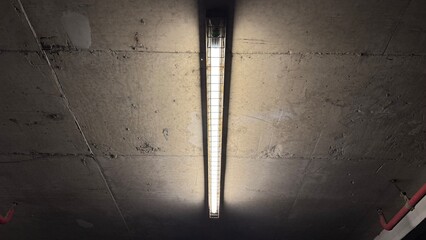 Fluorescent lights on the concrete ceiling of the garage at night.