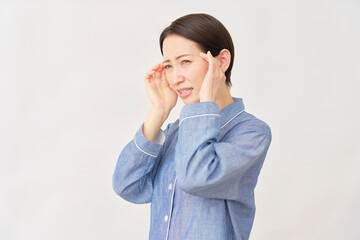 パジャマ姿の女性　頭痛　白背景