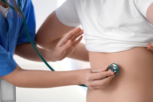 Female doctor with stethoscope listening to male patient in clinic, back view