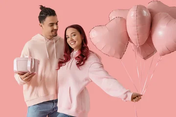 Fotobehang Onderzeeër Young lovely couple with gift and heart-shaped balloons on pink background. Valentine's Day celebration  © Pixel-Shot