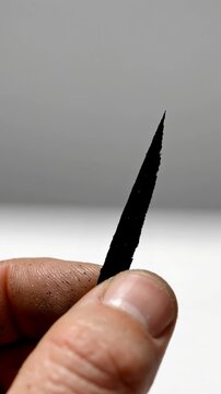 Dirty hand human finger thumb fingernail black shard sharp edge small piece closeup macro critical mineral resources human skin rugged hand holding shard fragment splinter danger risk industrial