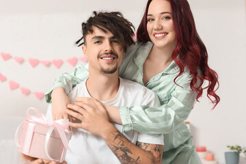 Young lovely couple with gift hugging at home. Valentine's Day celebration