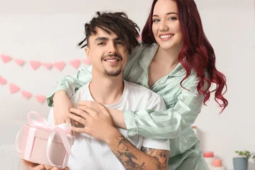 Fotobehang Onderzeeër Young lovely couple with gift hugging at home. Valentine's Day celebration  © Pixel-Shot
