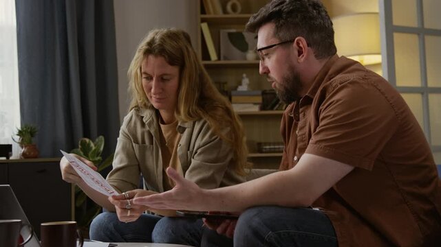 Side view shot of adult couple holding bills with past due notice and discussing home finances while doing budgeting together, copy space