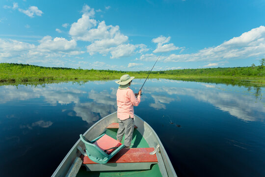 Woman on a Maine lake fishing from boat.