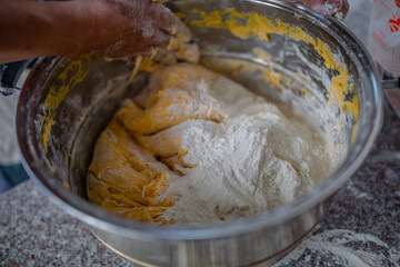 Fototapeta premium The Process of Mixing Batter in Baking with Hands Adding Flour into a Bowl of Egg Mixture