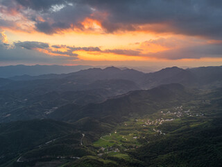 Obraz premium Breathtaking Sunset Over Majestic Mountains and Valleys with Dramatic Clouds and Golden Sky