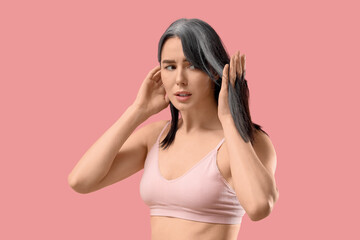 Worried young woman with graying hair on pink background