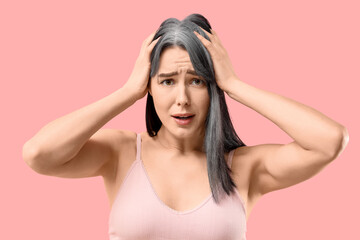 Worried young woman with graying hair on pink background