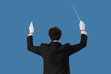 Young male conductor on blue background, back view
