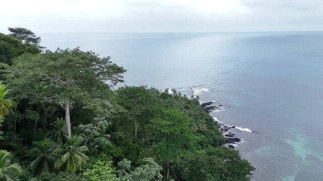 cinematic aerial view overlooking the vast and untouched equatorial forest of Sao Tome Island, Africa overlooking the Atlantic Ocean