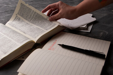 Naklejka premium Focused Individual Studying Chinese Grammar on Black Desk