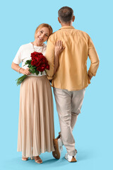 Happy mature couple with bouquet of roses and proposal ring on blue background. Valentine's Day...