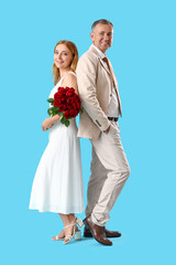 Happy mature couple with bouquet of roses on blue background. Valentine's Day celebration