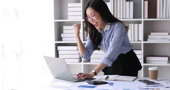 Young Asian professional business woman office worker analyst sitting at desk working on laptop thinking on project plan, analyzing marketing or financial data online, watching elearning webinar.