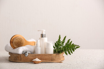 Tray with massage body brush and bottles of cosmetic products on white background, closeup