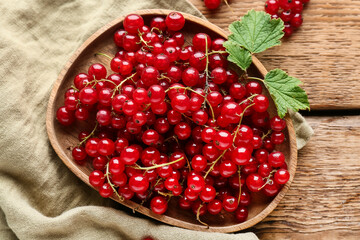 Plate with fresh red currants on wooden background © Pixel-Shot