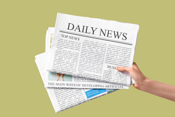 Naklejka premium Female hand with newspapers on green background
