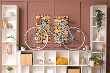 Modern bicycle on shelf near brown wall