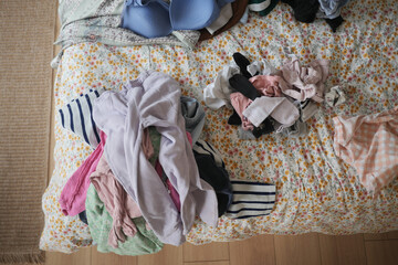 Clothes piled on a bed in a messy room