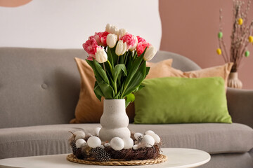 Vase with tulips and Easter wreath on table in living room © Pixel-Shot