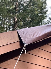 A brown tarp on a damaged metal roof
