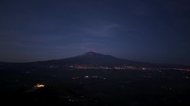 Approaching the glowing peak of mount Etna with lava erupting from the Italian volcano at night