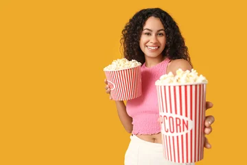 Fotobehang Onderzeeër Beautiful young African-American woman with buckets of tasty popcorn on yellow background  © Pixel-Shot