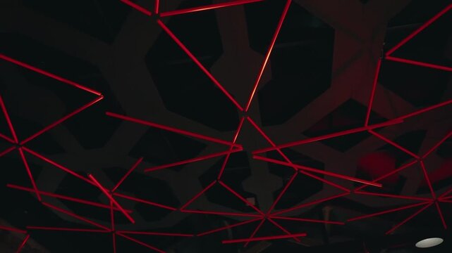 Red linear lights forming geometric pattern on dark ceiling