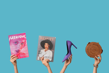 Female hands with different magazines, high heel and stylish bag on blue background