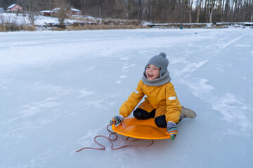 Child having fun in the snow, wearing winter clothing in snowy landscape during daytime. Child with a big smile surrounded by snowy trees and a clear blue sky.
