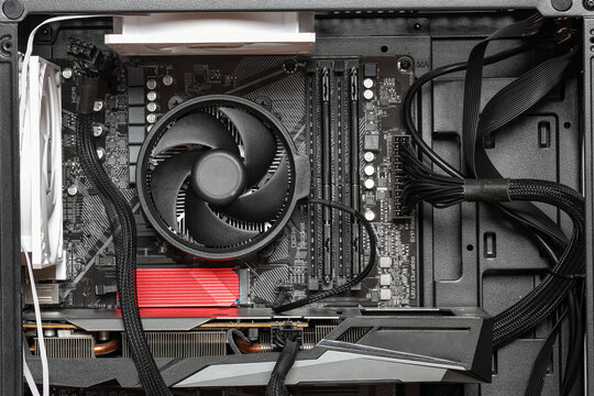 An open-side view of a gaming desktop reveals a cooling fan, graphics card, motherboard, RAM, and neatly organized cables inside a dark case.