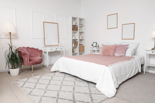 Stylish bedroom with cozy armchair, bed and shelving unit