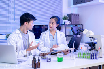 Fototapeta premium Woman scientist researcher holding document chart discussing work with colleague man in a lab room.