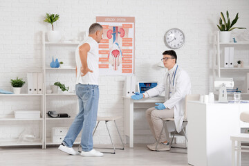 Young urologist working with mature man in office