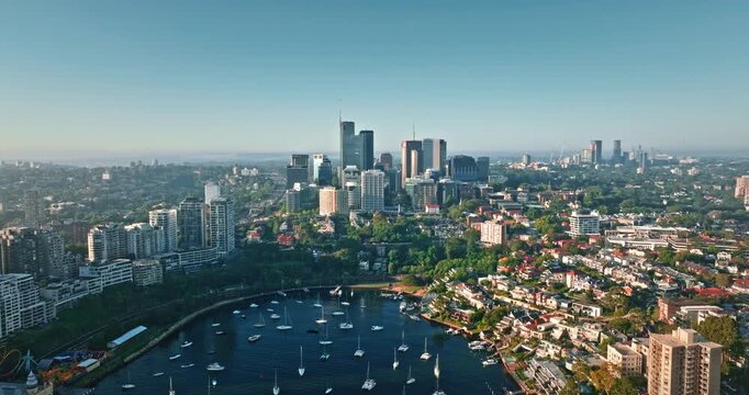 Aerial view of North Sydney skyline residential areas and calm water of Lavender Bay filled with many moored yachts under clear morning sky. Modern city downtown skyscrapers building, business center