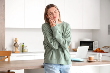 Young woman suffering from tooth ache at home