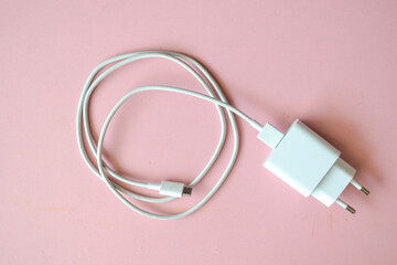 Mobile phone charger, white smartphone charger on pink background. Charger and USB cable type C on pink background