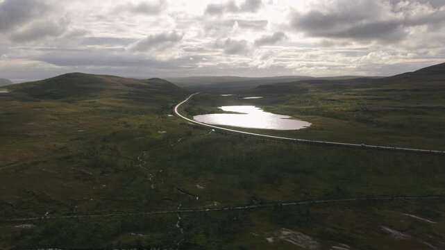 A Quiet Stretch of Road Curves Past Reflective Lakes and Open Tundra Along the E69 Road in Finnmark, Norway - Aerial Drone Shot