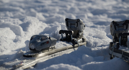 Close-up of ski bindings resting in fresh, sparkling snow on a sunny winter day
