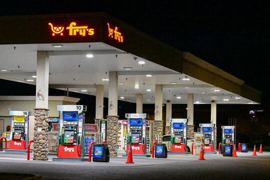 Gas station fuel pumps illuminated at night under canopy with fry&rsquo;s signage, representing retail fueling operations, consumer transportation services, and commercial convenience infrastructure