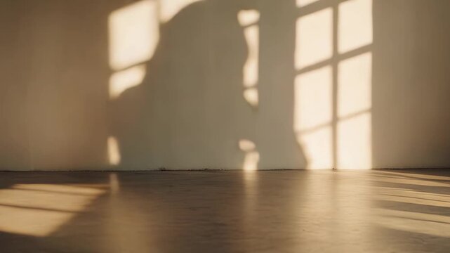Sunlight beams stream through a window, creating pronounced grid shadows on the white wall and warm wooden floor of an empty, minimalist room, providing an abstract background