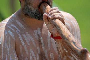 Indigenous Australians man play Aboriginal music with didgeridoo wind instrument